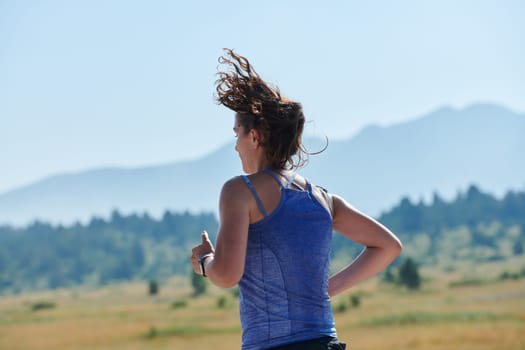 An athletic woman finds freedom and joy in a healthy lifestyle, running through a beautiful road trail at sunrise.