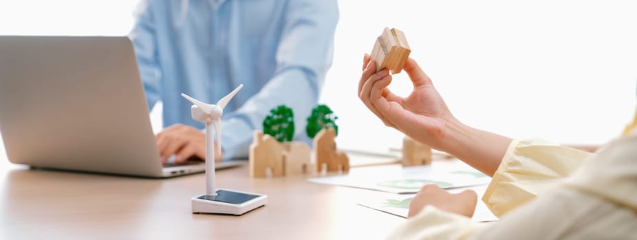 Businesswoman decides to Invest in green business. Skilled architects plan to build a eco house by using renewable energy at table with environmental document scatter around. Close up. Delineation.