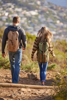 Vacation, hiking and couple walking in nature for holiday, travel or adventure outdoor with backpack. Rear view, man and woman trekking in the countryside on journey, date and exploration together.