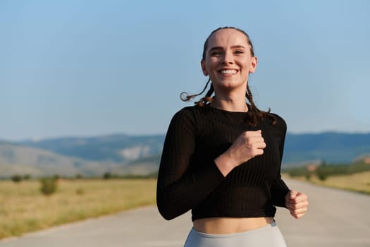 An athletic woman finds freedom and joy in a healthy lifestyle, running through a beautiful road trail at sunrise.