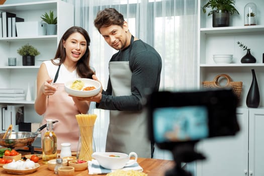 Couple chef influencers completely cooked spaghetti with meat topped with tomato sauce special dish recording on camera with live chanel. Concept of serving healthy food at modern home. Postulate.