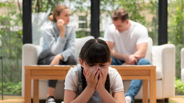 Stressed and unhappy young girl crying and trapped in middle of tension by her parent argument in living room. Unhealthy domestic lifestyle and traumatic childhood depression. Panorama Synchronos