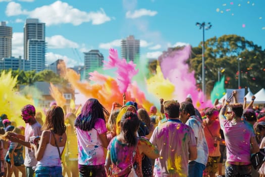 Revelers enjoy a Holi event in Sydney, Australia, captured mid-celebration as clouds of colorful powder fill the air. The festive atmosphere is palpable, with city buildings standing tall in the background.