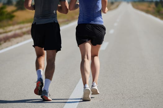 A vibrant couple dashes running the outdoors, embodying the essence of athleticism and romance, their confident strides reflecting a shared commitment to fitness and preparation for future marathon challenges.