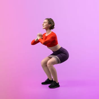 Full body length gaiety shot athletic and sporty young woman with fitness elastic resistance band in squat exercise posture on isolated background. Healthy active and body care lifestyle.