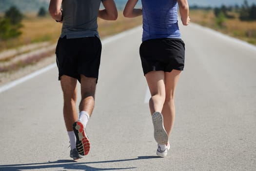 A vibrant couple dashes running the outdoors, embodying the essence of athleticism and romance, their confident strides reflecting a shared commitment to fitness and preparation for future marathon challenges.