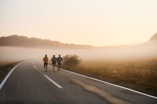A group of friends, athletes, and joggers embrace the early morning hours as they run through the misty dawn, energized by the rising sun and surrounded by the tranquil beauty of nature.