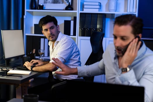 Creative professional freelancers with serious face discussing the solutions with new customer on smartphone calling at workplace. In casual office with night time waiting at work from home. Sellable.