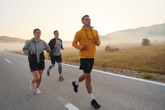 A group of friends, athletes, and joggers embrace the early morning hours as they run through the misty dawn, energized by the rising sun and surrounded by the tranquil beauty of nature.