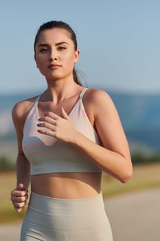 An athletic woman finds freedom and joy in a healthy lifestyle, running through a beautiful road trail at sunrise.