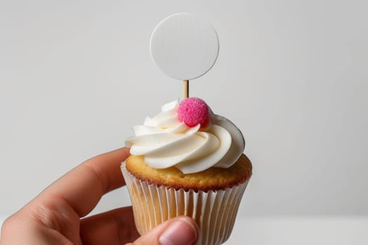 Cupcake with white cream and an inscription plate on a white background.