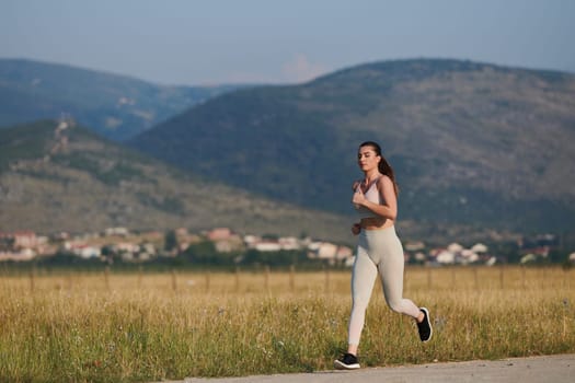 An athletic woman finds freedom and joy in a healthy lifestyle, running through a beautiful road trail at sunrise.