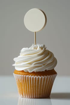 Cupcake with white cream and an inscription plate on a white background.