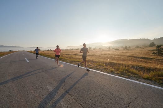 A group of friends, athletes, and joggers embrace the early morning hours as they run through the misty dawn, energized by the rising sun and surrounded by the tranquil beauty of nature.