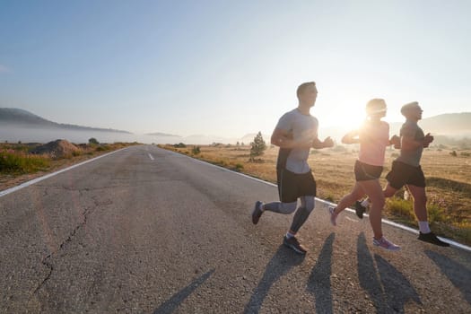 A group of friends, athletes, and joggers embrace the early morning hours as they run through the misty dawn, energized by the rising sun and surrounded by the tranquil beauty of nature.