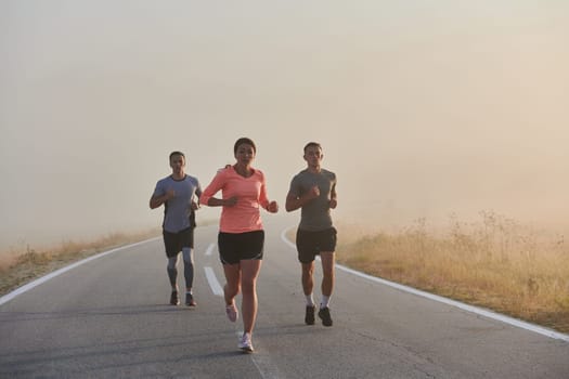 A group of friends, athletes, and joggers embrace the early morning hours as they run through the misty dawn, energized by the rising sun and surrounded by the tranquil beauty of nature.