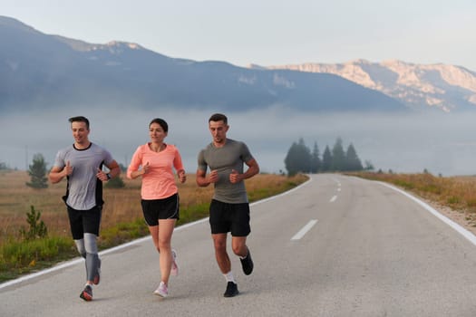 A group of friends, athletes, and joggers embrace the early morning hours as they run through the misty dawn, energized by the rising sun and surrounded by the tranquil beauty of nature.