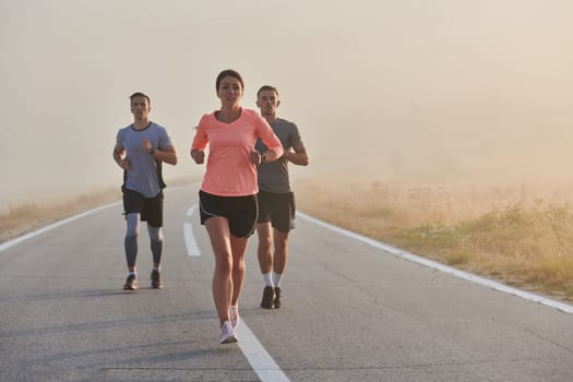 A group of friends, athletes, and joggers embrace the early morning hours as they run through the misty dawn, energized by the rising sun and surrounded by the tranquil beauty of nature.