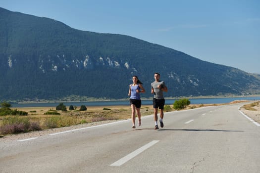 A couple runs through a sun-dappled road, their bodies strong and healthy, their love for each other and the outdoors evident in every stride.