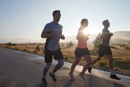 A group of friends, athletes, and joggers embrace the early morning hours as they run through the misty dawn, energized by the rising sun and surrounded by the tranquil beauty of nature.