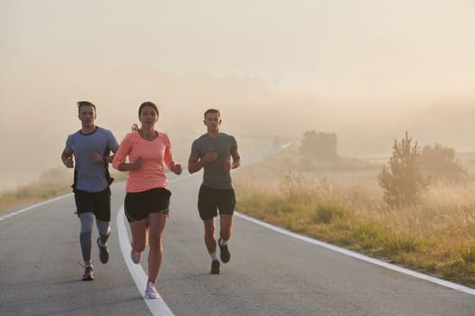 A group of friends, athletes, and joggers embrace the early morning hours as they run through the misty dawn, energized by the rising sun and surrounded by the tranquil beauty of nature.