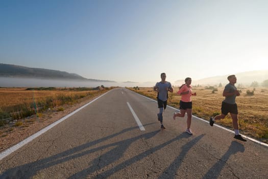 A group of friends, athletes, and joggers embrace the early morning hours as they run through the misty dawn, energized by the rising sun and surrounded by the tranquil beauty of nature.