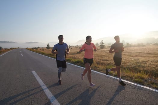 A group of friends, athletes, and joggers embrace the early morning hours as they run through the misty dawn, energized by the rising sun and surrounded by the tranquil beauty of nature.