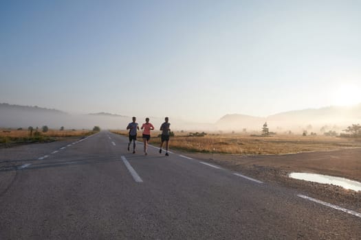 A group of friends, athletes, and joggers embrace the early morning hours as they run through the misty dawn, energized by the rising sun and surrounded by the tranquil beauty of nature.