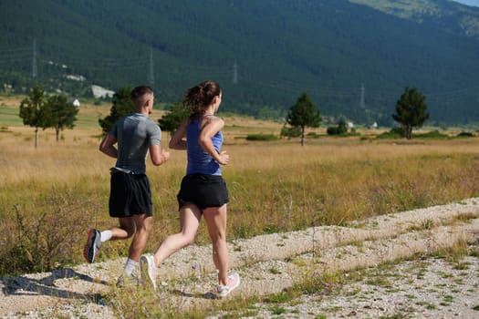 A vibrant couple dashes running the outdoors, embodying the essence of athleticism and romance, their confident strides reflecting a shared commitment to fitness and preparation for future marathon challenges.