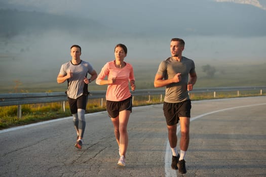 A group of friends, athletes, and joggers embrace the early morning hours as they run through the misty dawn, energized by the rising sun and surrounded by the tranquil beauty of nature.