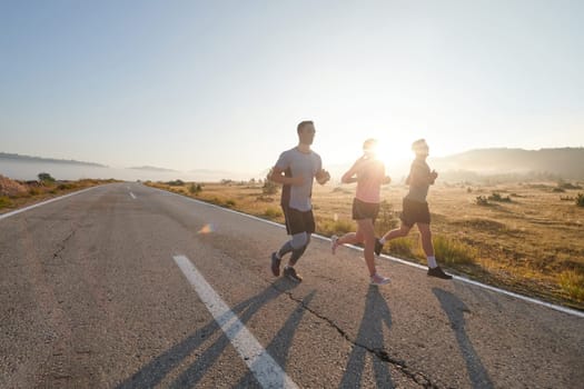 A group of friends, athletes, and joggers embrace the early morning hours as they run through the misty dawn, energized by the rising sun and surrounded by the tranquil beauty of nature.