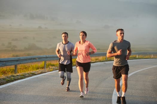 A group of friends, athletes, and joggers embrace the early morning hours as they run through the misty dawn, energized by the rising sun and surrounded by the tranquil beauty of nature.