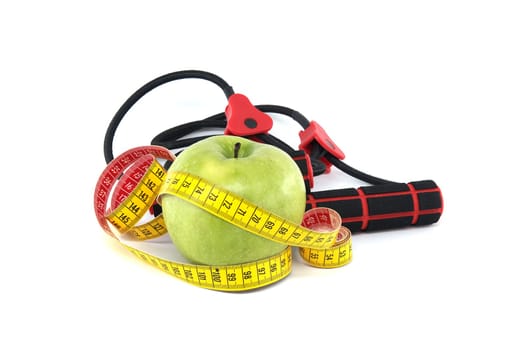 Green apple and yellow measuring tape in front of resistance band isolated on white background, healthy living and exercise