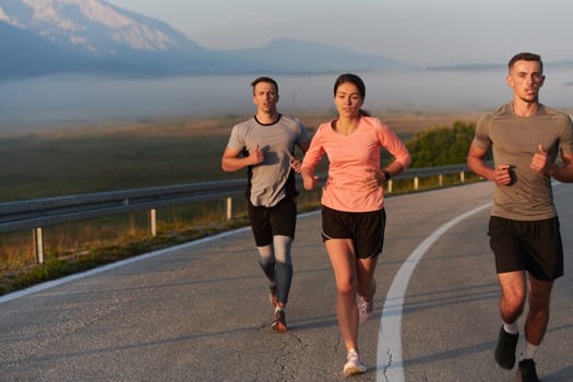 A group of friends, athletes, and joggers embrace the early morning hours as they run through the misty dawn, energized by the rising sun and surrounded by the tranquil beauty of nature.