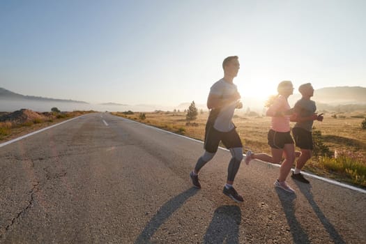 A group of friends, athletes, and joggers embrace the early morning hours as they run through the misty dawn, energized by the rising sun and surrounded by the tranquil beauty of nature.