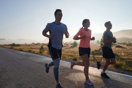 A group of friends, athletes, and joggers embrace the early morning hours as they run through the misty dawn, energized by the rising sun and surrounded by the tranquil beauty of nature.