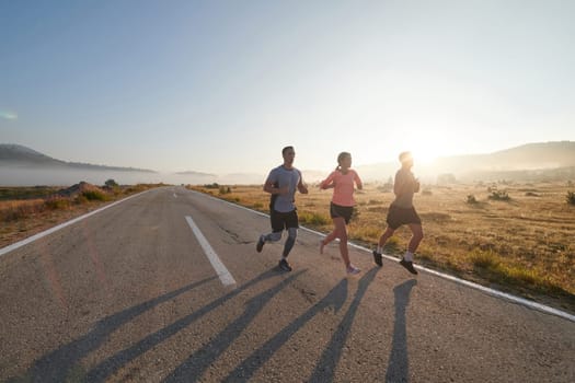 A group of friends, athletes, and joggers embrace the early morning hours as they run through the misty dawn, energized by the rising sun and surrounded by the tranquil beauty of nature.