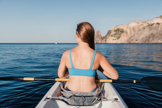 Woman in kayak back view. Happy young woman with long hair floating in transparent kayak on the crystal clear sea. Summer holiday vacation and cheerful female people relaxing having fun on the boat