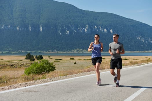 A couple runs through a sun-dappled road, their bodies strong and healthy, their love for each other and the outdoors evident in every stride.