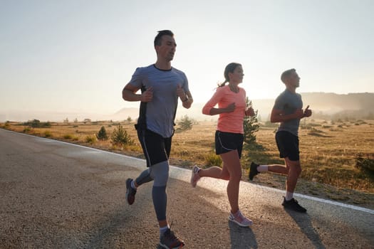 A group of friends, athletes, and joggers embrace the early morning hours as they run through the misty dawn, energized by the rising sun and surrounded by the tranquil beauty of nature.