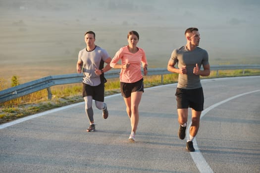 A group of friends, athletes, and joggers embrace the early morning hours as they run through the misty dawn, energized by the rising sun and surrounded by the tranquil beauty of nature.