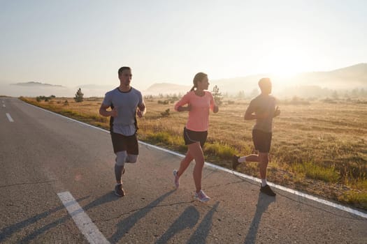 A group of friends, athletes, and joggers embrace the early morning hours as they run through the misty dawn, energized by the rising sun and surrounded by the tranquil beauty of nature.