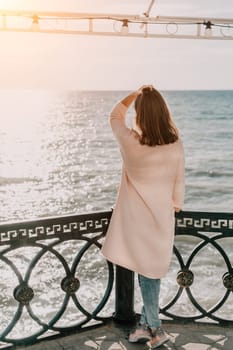 Woman travel sea. Young Happy woman in a long red dress posing on a beach near the sea on background of volcanic rocks, like in Iceland, sharing travel adventure journey