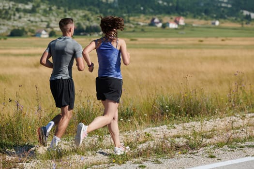 A vibrant couple dashes running the outdoors, embodying the essence of athleticism and romance, their confident strides reflecting a shared commitment to fitness and preparation for future marathon challenges.