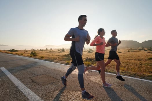 A group of friends, athletes, and joggers embrace the early morning hours as they run through the misty dawn, energized by the rising sun and surrounded by the tranquil beauty of nature.