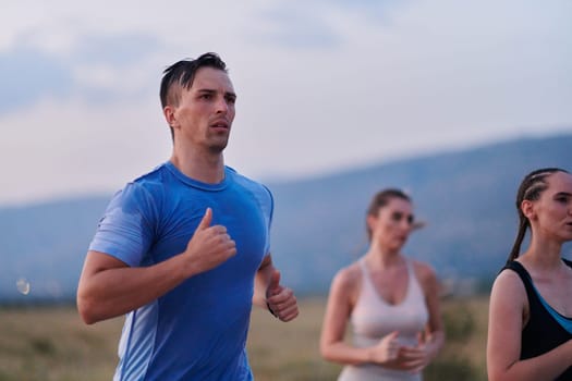 A diverse group of runners finds motivation and inspiration in each other as they train together for an upcoming competition, set against a breathtaking sunset backdrop.