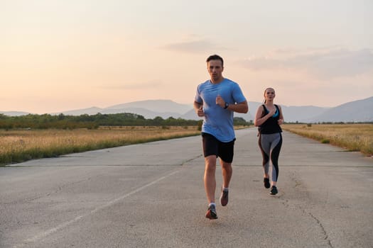 A vibrant couple dashes running the outdoors, embodying the essence of athleticism and romance, their confident strides reflecting a shared commitment to fitness and preparation for future marathon challenges.