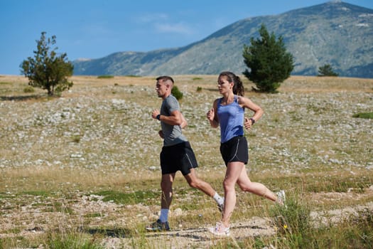 A vibrant couple dashes running the outdoors, embodying the essence of athleticism and romance, their confident strides reflecting a shared commitment to fitness and preparation for future marathon challenges.