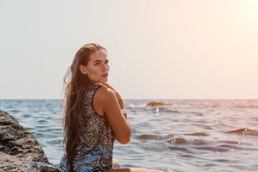 Woman travel sea. Young Happy woman in a long red dress posing on a beach near the sea on background of volcanic rocks, like in Iceland, sharing travel adventure journey