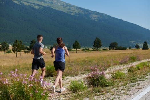 A vibrant couple dashes running the outdoors, embodying the essence of athleticism and romance, their confident strides reflecting a shared commitment to fitness and preparation for future marathon challenges.